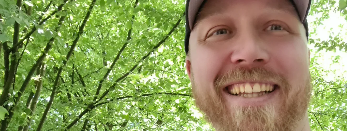 Porträt von Christoph Bußinger, Autor und Gründer, mit Schildmütze und rotem Rucksack – bereit für neue Projekte.